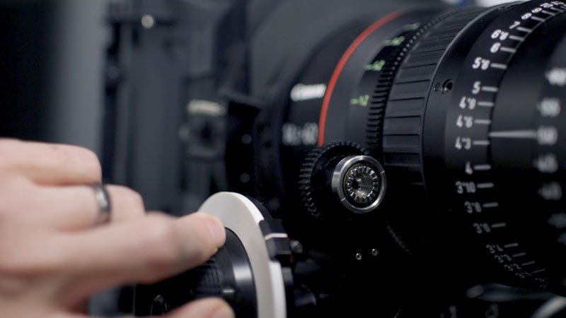 A focus puller operating a follow focus on a cine lens
