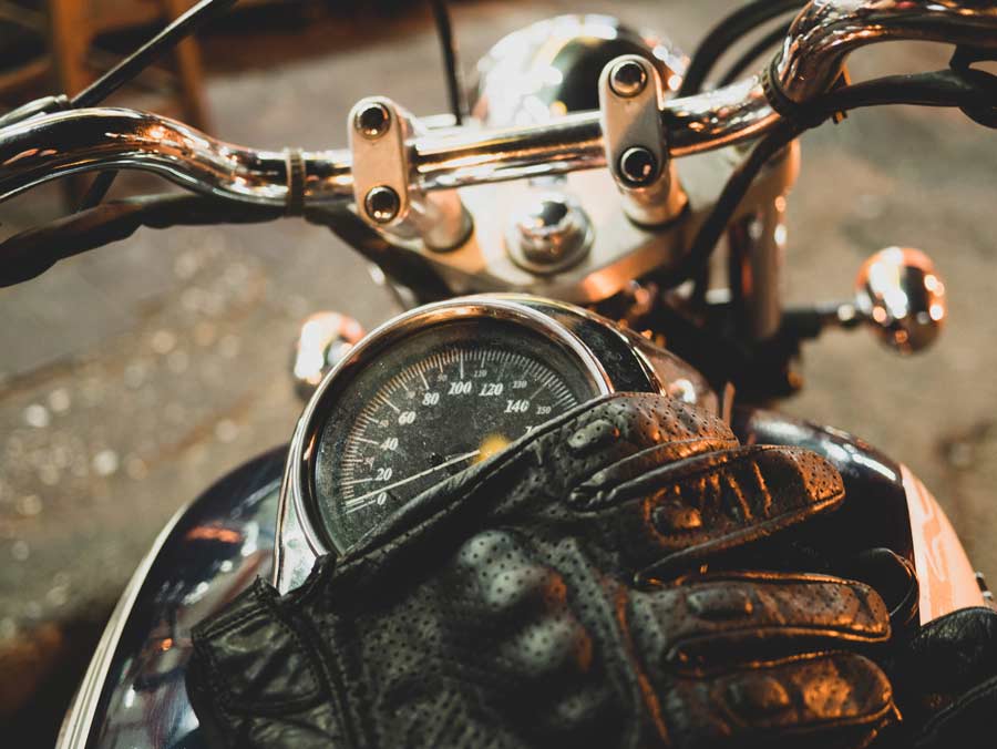 Leather motorcycle gloves on chrome bike's speedometer