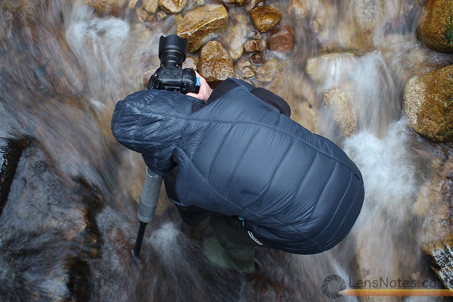 Photographer with a camera on a tripod in a fast moving river